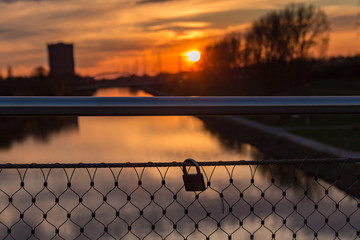 Lovelocks on a bridge railing with the light of the setting sun at the Rhein-Herne-Canal in...
