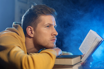 Obraz premium Side view pensive bearded male looking through book while leaning on table. Study concept