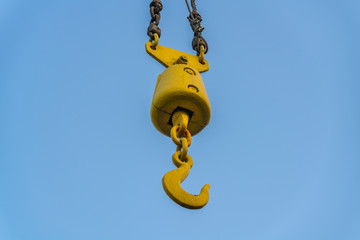 Yellow crane hook with blue sky, seen in Duisburg-Ruhrort, North Rhine-Westphalia, Germany