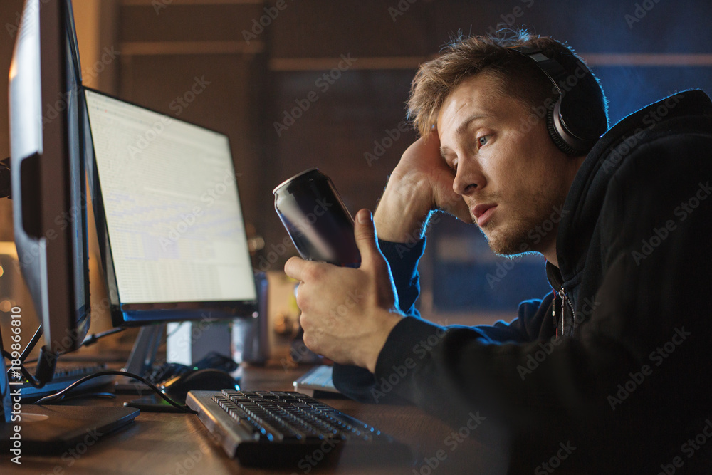 Aufkleber side view tired male watching at can of alcohol drink while hearing song. he working with computer a
