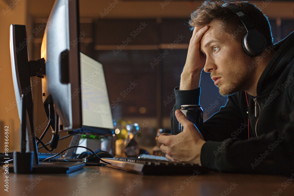 Poster what is it. side view surprised unshaven man watching at display of computer while drinking alcohol 