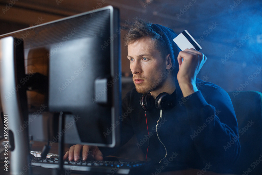 Poster portrait of calm bearded hacker stealing money. he working with computer. crime concept