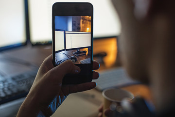 Close up man hand holding mobile. He taking photo of screen of digital device while sitting at table. Technology concept © Yakobchuk Olena