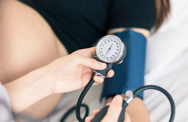 Female Obstetrician doctor  measuring blood pressure of the pregnant woman in the hospital....