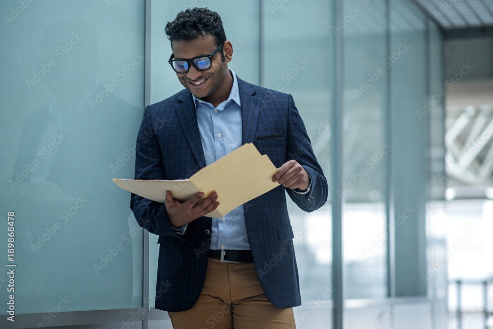 Poster documents check. skillful young appealing businessman is working with documents and staring at them 