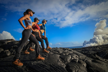 A group of three girls wearing trekking shoes standing on black lava field