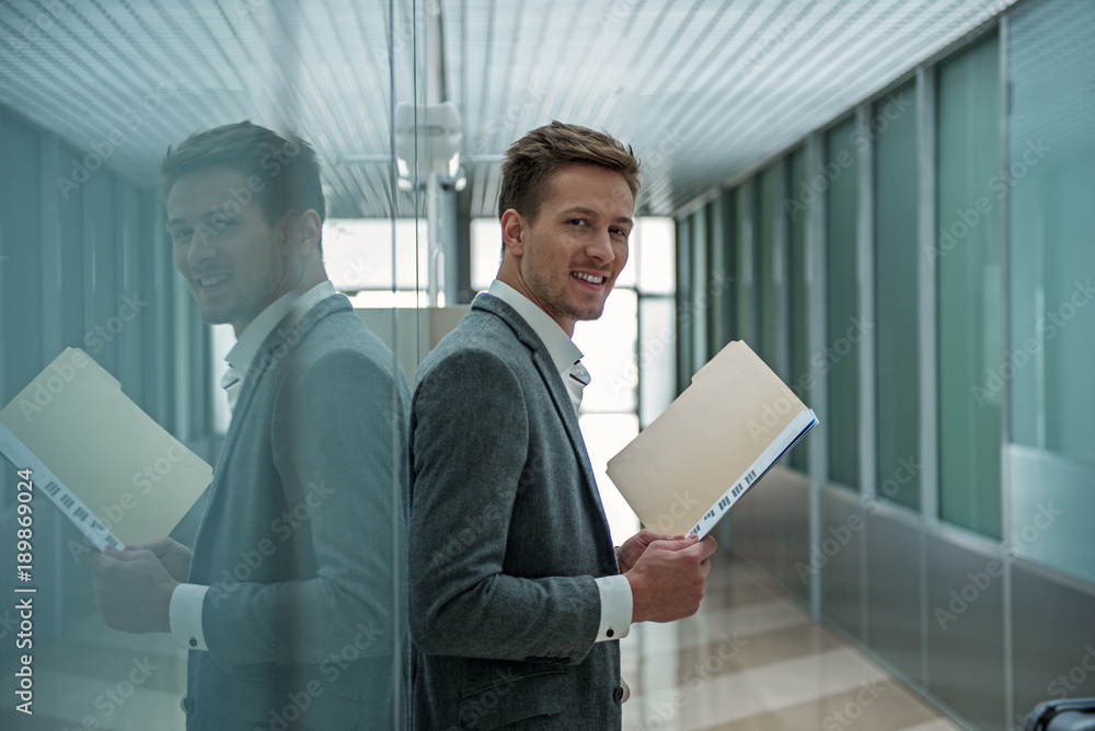 Poster productive day. young cheerful man is looking at camera with joy while standing with opened document