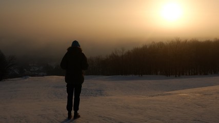 The guy (young man) looking at the sunrise in a frosty morning.