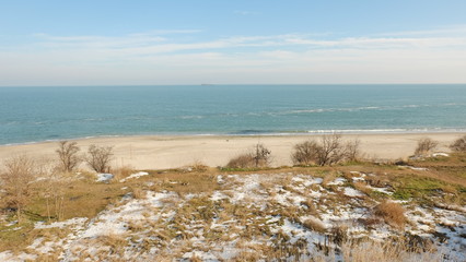 Landscape on the shore of the sea with snow and blue sky.