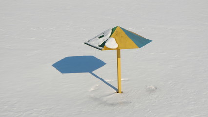 Colorful sun umbrella on a white snowy background.