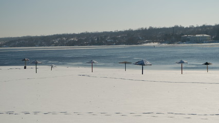 Snowy bank of the Dnipro River with sun umbrellas.