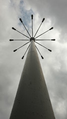 A pillar with a few lanterns against a cloudy sky.