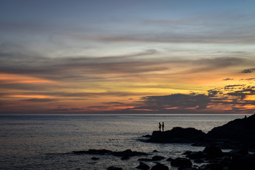 fisher at cliff coast during sunset