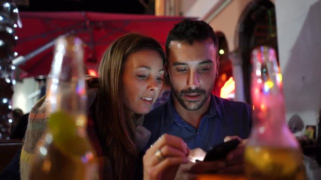 Couple in restaurant at night using smartphone