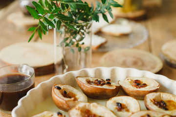 dish with baked half of pears, steam, mugs with coffee on a wooden table