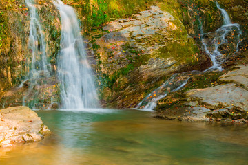 Fototapeta na wymiar The cascade waterfall of the mountain river Bezumenka closeup in sunny autumn day, Sochi, Russia 