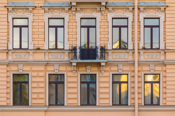 Fototapeta na wymiar Several windows in a row and balcony on the facade of the urban historic building front view, Saint Petersburg, Russia 