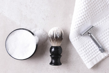 Safety razor on a towel with brush and soap on a gray tile surface