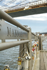 Closeup of love locks in fence with East River of New York City on the background