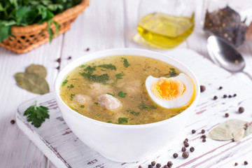 Dietary soup with chicken meatballs and egg on white wooden background