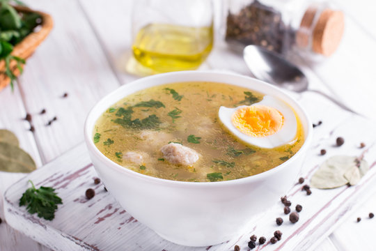 Dietary soup with chicken meatballs and egg on white wooden background