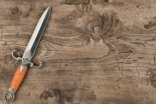 Knife, dagger on a wooden surface, with a place for your text.