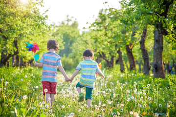 Fototapeta premium Two happy children playing in garden with windmill