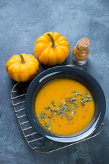 Plate of freshly made pumpkin cream-soup over blue stone background, high angle view, vertical shot