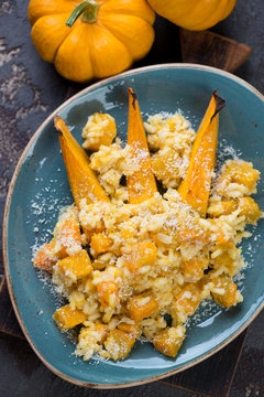 Above view of pumpkin risotto with parmesan cheese on a turquoise plate, vertical shot