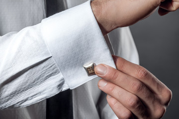 A man adjusts the cufflink on the sleeve of his shirt