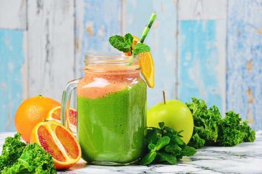 Fresh Green Smoothies with blood oranges. Green smoothie jar on the light background