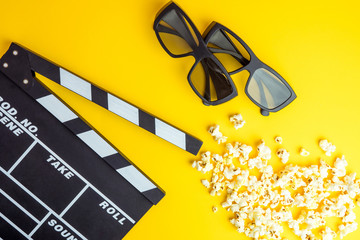 Cinema minimal concept. Watching film in the cinema. 3d glasses, popcorn, clapper board on yellow...