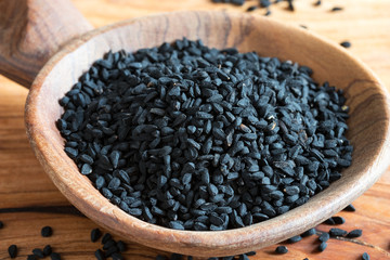 Fototapeta na wymiar Black cumin seeds on a wooden background