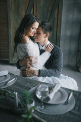 A young woman sits on man's lap in the kitchen. Couple in love.