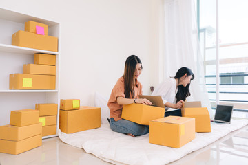 Freelancer asian women teamwork sme business working at office in home interior writing address,packing order for customer and online delivery for ready packing on working table