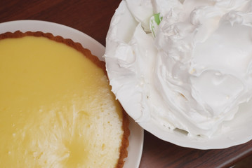 Preparing Lemon Pie. Lemon Pie and Bowl with Meringue Cream Ready to be Decorated on Wooden table, closeup.