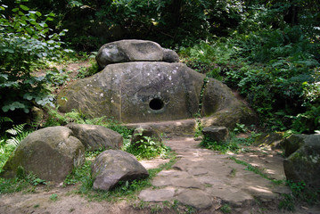 Ancient monolithic dolmen (single-chamber megalithic tomb) with a round hole in the mountain forest...