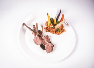 Lamb chops, braised lentils with mint, roast vegetables and rosemary sauce on a white background
