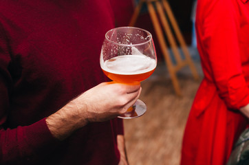 a young man holding a glass of light beer. a party in the circle of friends. alcohol party