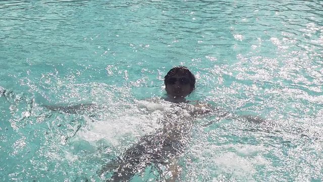 Man in sunglasses relaxing under pool waterfall in swimming pool, slow motion. 1920x1080