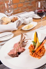 Lamb chops, braised lentils with mint, roast vegetables and rosemary sauce served in a restaurant