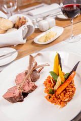 Lamb chops, braised lentils with mint, roast vegetables and rosemary sauce served in a restaurant