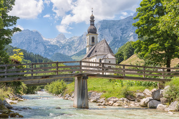 Church of Ramsau near Berchtesgaden in German Bavarian alps with a river and wooden bridge in front