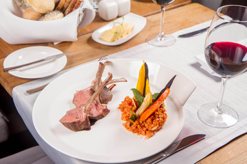 Lamb chops, braised lentils with mint, roast vegetables and rosemary sauce served in a restaurant