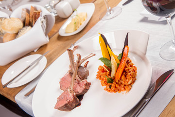Lamb chops, braised lentils with mint, roast vegetables and rosemary sauce served in a restaurant
