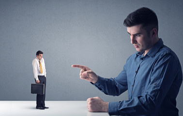 Young businessman fighting with miniature businessman