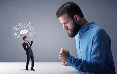 Young businessman fighting with miniature businessman