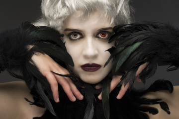 Androgynous witch girl, with red-green eyes and black feathers, crying black star