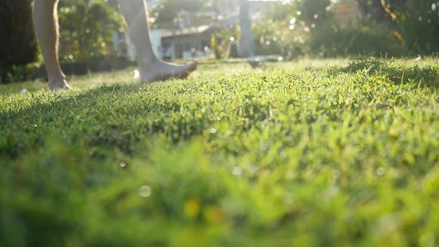 Man with naked feet walking on the grass on sunny day with lens flare effects in slow motion. Healthy lifestyle. 1920x1080
