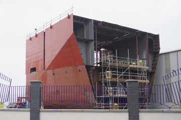 Shipbuilding in progress scaffold erected around large steel ship in yard